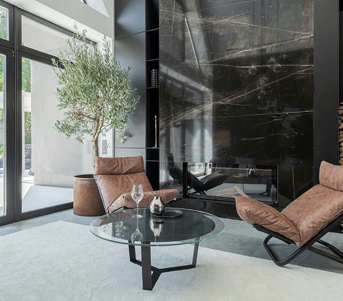 Lounge with tile fireplace, elegant furniture, and large windows.
