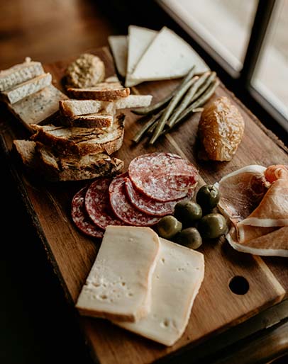 Charcuterie board with meats, cheeses, breads, and olives.