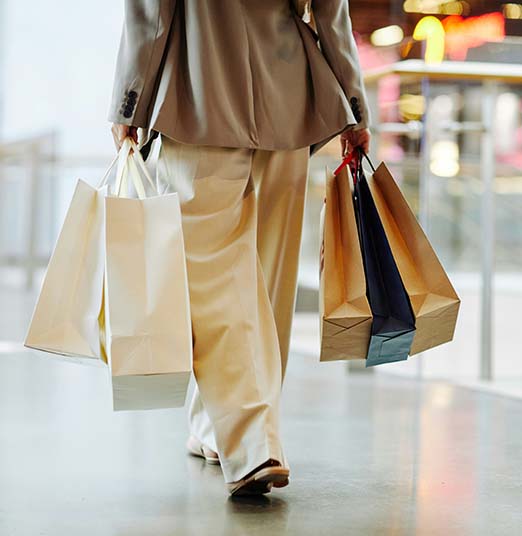 Person walking in shopping mall carrying shopping bags.