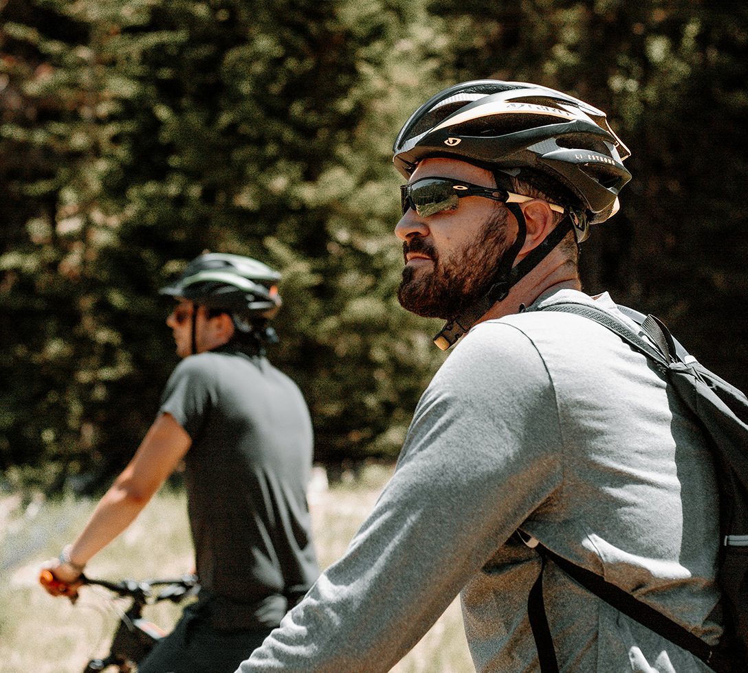 Two friends riding bikes together outdoors.