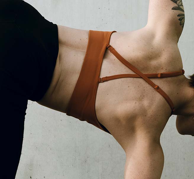 Person in sports bra and yoga pants holding yoga pose.