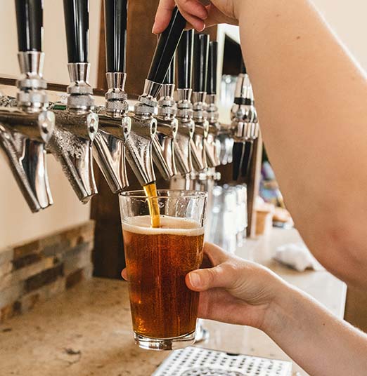 Person pouring pint of beer from a tap.