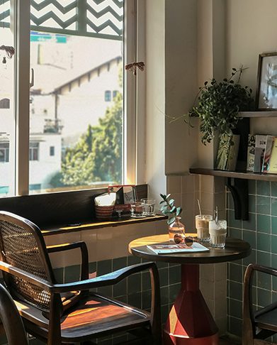 Cafe with eclectic seating and decor and large windows.