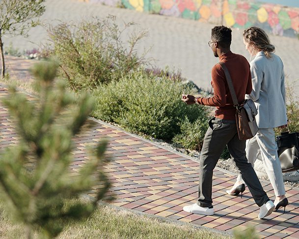 Two friends walking together along brick walkway.