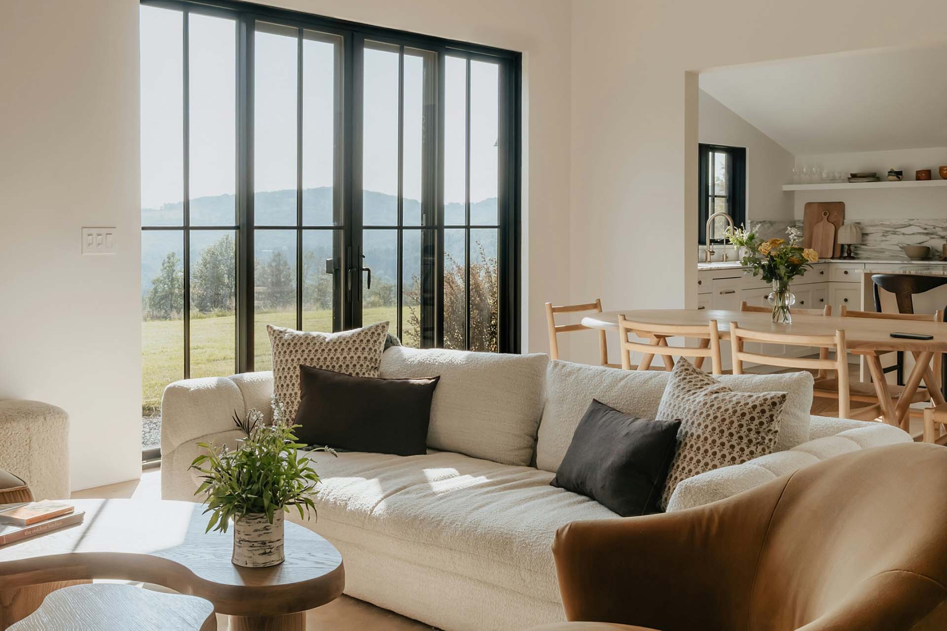 Living area with plush seating, wood dining table, and modern kitchen.