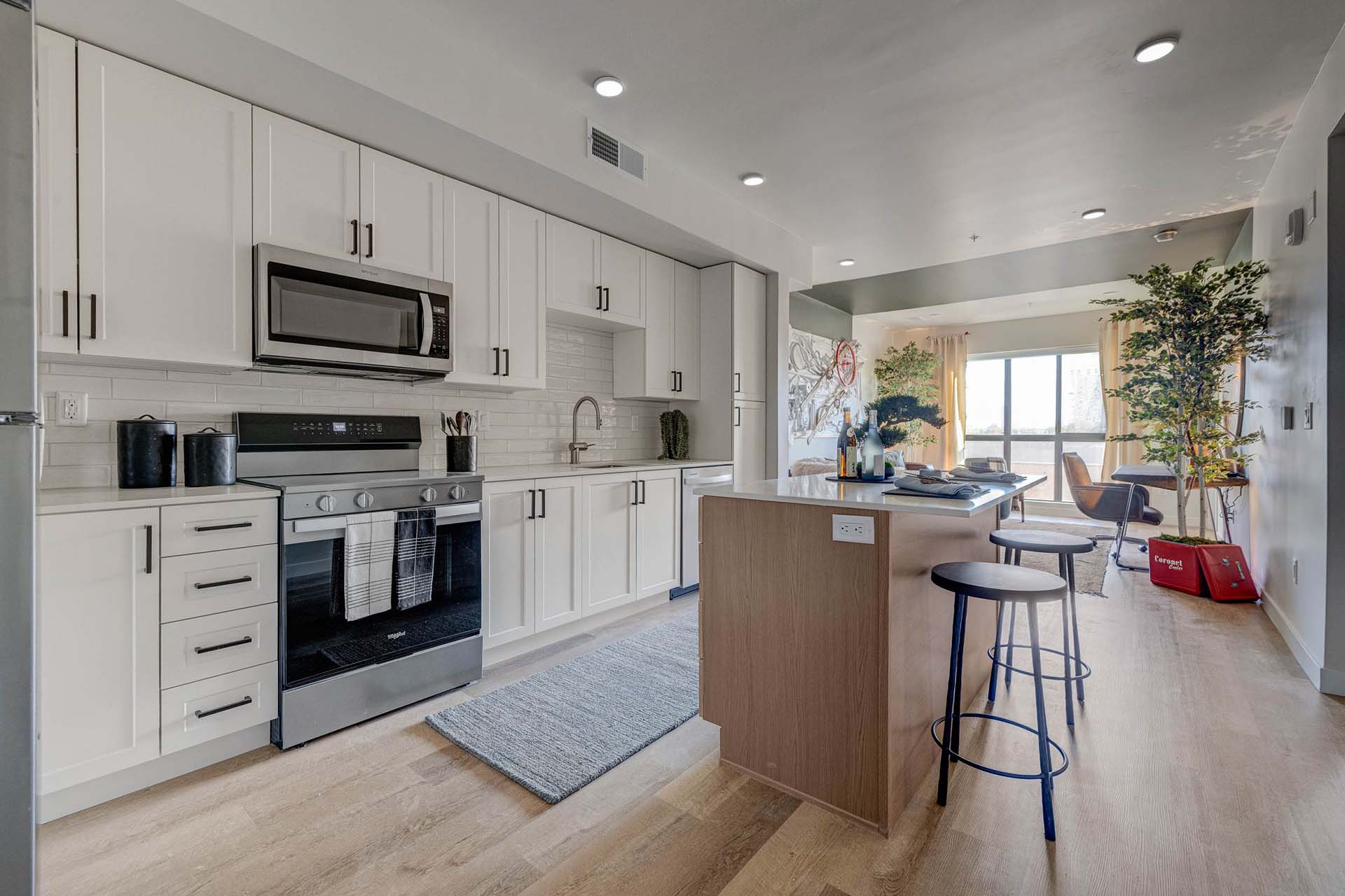 Millhaus apartment kitchen with wood style floor, stainless steel appliances, and kitchen island.